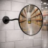 450mm Vista Flex indoor convex mirror mounted on a warehouse wall with adjustable arm and wall plate, showing warehouse aisle reflection and size dimensions